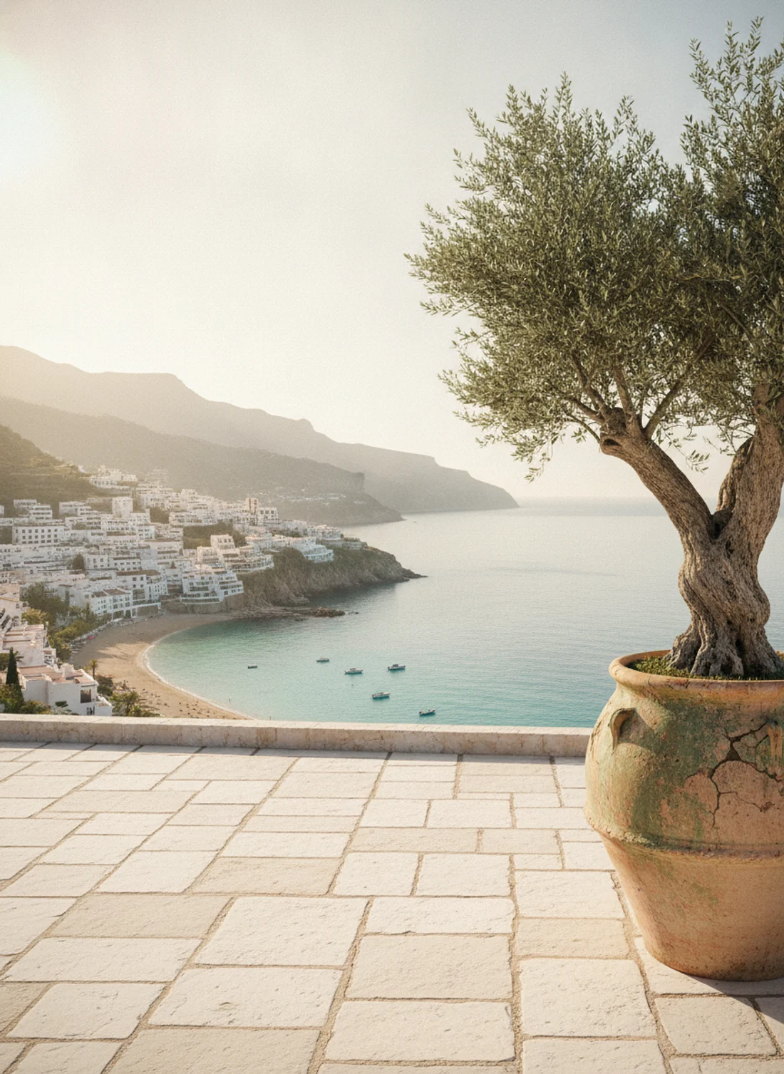 Mediterranean terrace with an olive tree overlooking a whitewashed coastal village and the sea
